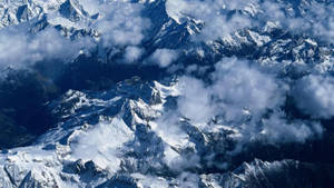在廣闊的高山景觀中，積雪的山峰聳立於雲層之上。 — 唐人街 GIF 壁紙