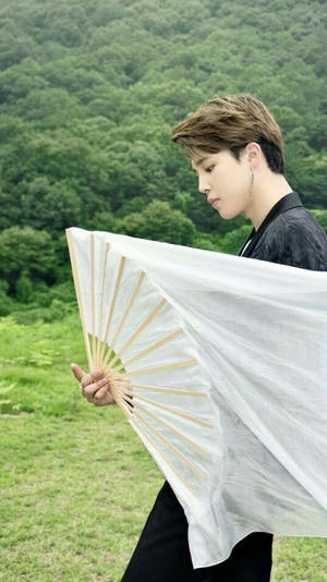 年輕男子在綠色森林中手持白色扇子 — Jimin GIF 壁紙