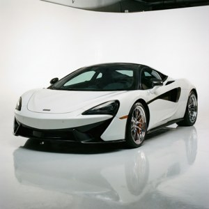 白色McLaren跑車，帶有黑色飾件和金色制動卡鉗，在一個帶有反射地板的工作室中。