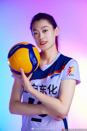女排球運動員在色彩繽紛的燈光工作室中拿著一個球。