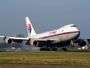 MASkargo波音747貨機降落在跑道上，揚起灰塵雲。