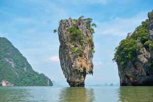 高聳的石灰岩島嶼從平靜的海水中升起，周圍是叢林覆蓋的懸崖。 — 島嶼 壁紙