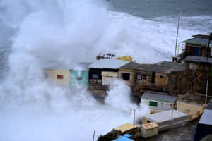 暴風雨中，強大的海浪沖刷著小型沿海建築。 — 雷暴 壁紙