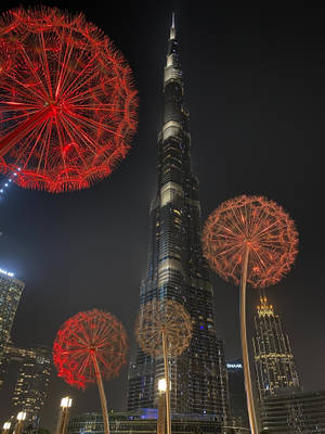 紅色蒲公英雕塑在哈利法塔旁照亮夜晚。 — 夜晚 GIF 壁紙