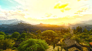 中世紀村莊在夕陽下，背景是綠色山丘和白雪覆蓋的山脈