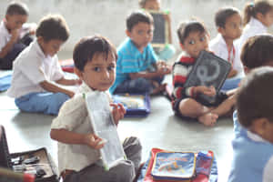 年幼的孩子坐在教室地板上拿著黑板