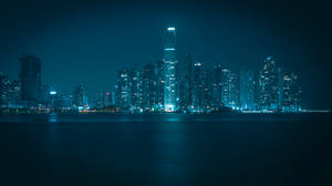 夜間城市天際線，燈火通明的建築物倒映在水中。 — 夜晚 GIF 壁紙
