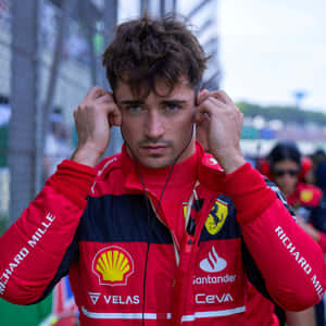 F1車手穿著紅色法拉利裝備在賽道上調整耳機。