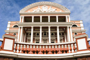 宏偉的新古典主義劇院，配有白色圓柱和赤陶欄杆，在藍天下。