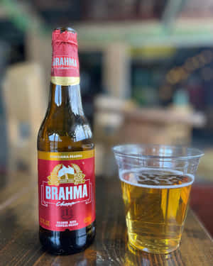 Brahma啤酒瓶和玻璃杯在酒吧的木桌上。