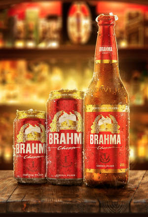 三罐冰凍的 Brahma 啤酒罐和一瓶啤酒放在溫暖燈光的酒吧木吧台上。