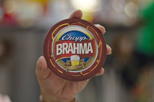 手拿著帶有標誌和小麥設計的 Brahma 啤酒杯墊。