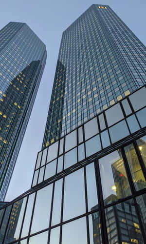 現代玻璃摩天大樓在暮色天空中聳立，窗戶亮著燈。 — Huawei Pura X View 壁紙