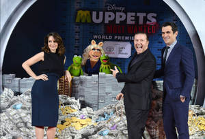 名人與 Muppet 在電影首映禮上站在一堆錢上。