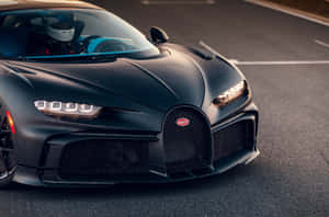 啞光黑色Bugatti Chiron，司機戴著頭盔，在日落時分的瀝青路上。