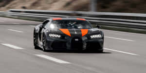 黑色和橙色的Bugatti Chiron Super Sport 300+在日落時分的賽道上飛馳。 — 汽車 壁紙