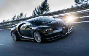 日落時分，黑色Bugatti Chiron在道路上奔馳，背景有樹木。