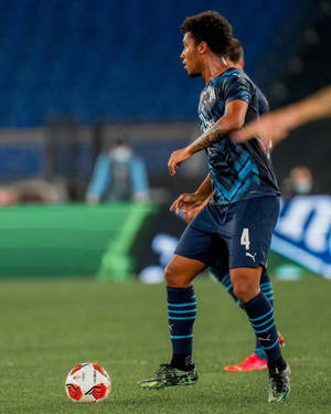 足球運動員在夜間球場燈光下的草地上運球。