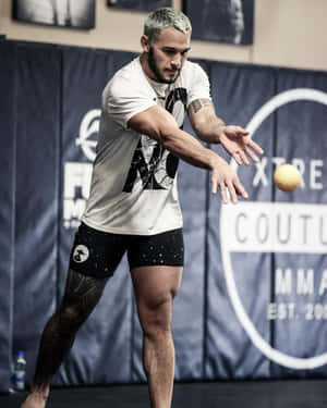 運動員在掛有品牌橫額的MMA健身室內投擲黃色球。 — 健身 壁紙