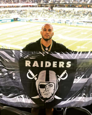 球迷在足球場上比賽期間舉起Raiders旗幟。
