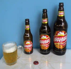 三瓶 Brahma 啤酒和一個裝滿啤酒的馬克杯放在有圖案的桌子上。