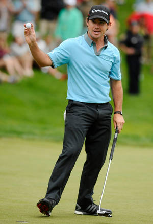 職業高爾夫球手Rory McIlroy在果嶺上慶祝，手持高爾夫球和推桿。 — 運動 壁紙