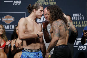 兩名MMA拳手在UFC過磅活動中，背景有粉絲和標誌，互相凝視。