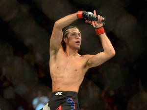 MMA拳手在八角籠內舉起拳頭慶祝勝利。