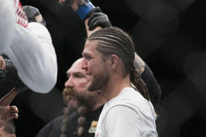 紮辮嘅MMA拳手喺場館同隊友慶祝勝利。