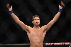 MMA選手在八角籠中高舉雙臂慶祝勝利。