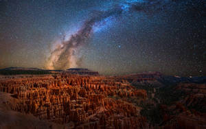 星空下，銀河系在橙色岩層上方閃耀。 — 銀河系 壁紙