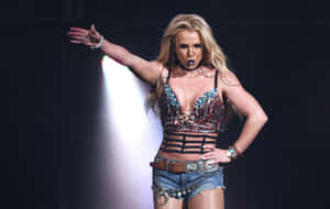 Britney Spears 在舞台上穿著亮片上衣和牛仔短褲表演。