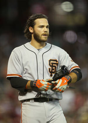 身穿巨人隊球衣的棒球運動員在夜間比賽中手持頭盔和手套。