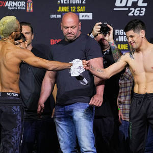 兩名MMA拳手在UFC稱重活動中握手，達納·懷特手持毛巾。