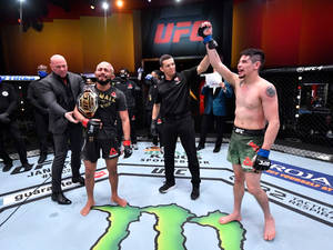 UFC 拳手在八角籠中慶祝勝利，裁判舉起他的手。