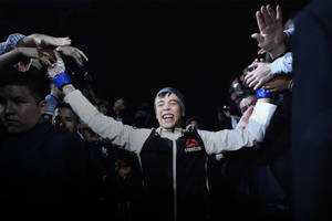 拳手舉起雙臂慶祝勝利，粉絲們伸手觸摸他的手套。