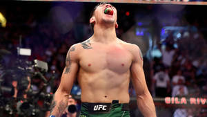 UFC拳手在八角籠中展示牙套和紋身慶祝勝利。