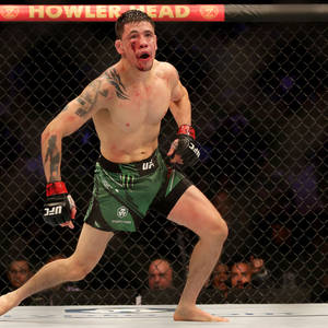 一名血跡斑斑的MMA拳手在八角籠內慶祝勝利。