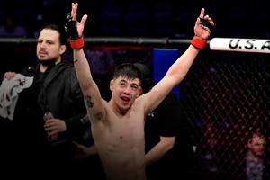 MMA 選手在八角籠中高舉雙臂慶祝勝利。