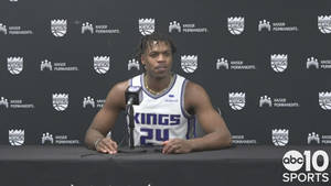 身穿Kings球衣的籃球運動員在記者會上拿著麥克風。
