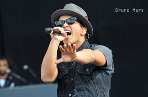 Bruno Mars 戴著太陽眼鏡和紳士帽在舞台上現場表演。