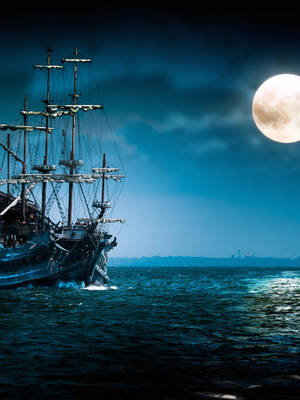 海盜船在夜間滿月下航行於黑暗的海洋上。