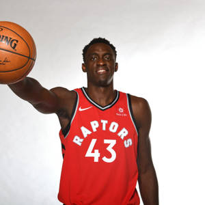身穿紅色Raptors球衣的職業籃球運動員持球。