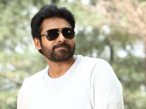 戴太陽眼鏡和留鬍鬚的男人，穿著白色毛衣在戶外。