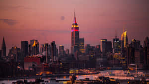 紐約市天際線在黃昏時分，閃耀的摩天大樓和紫色天空。 — 黃昏 壁紙