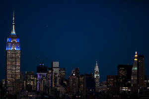 紐約市夜景天際線，摩天大樓燈火通明，黑暗天空中可見一顆星星。