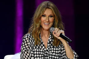 Celine Dion 在舞台上微笑著拿著咪高峰。
