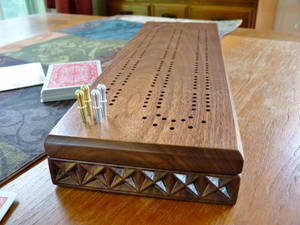 木製克里比奇棋盤，帶有黃銅和銀色棋子，以及桌上的撲克牌。