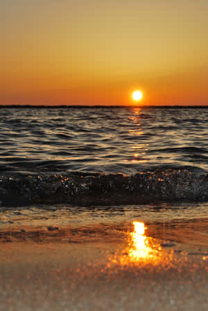 夕陽映照海洋，海浪沖刷沙灘