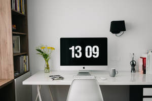 乾淨現代的書桌，iMac 顯示日期 13 09，周圍環繞書籍和鮮花。